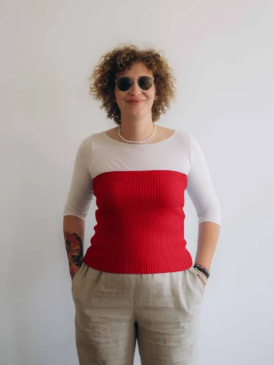 Modelka v bielom outfite TATTJA s červeným pleteným driekovníkom NATASJA, pohľad spredu