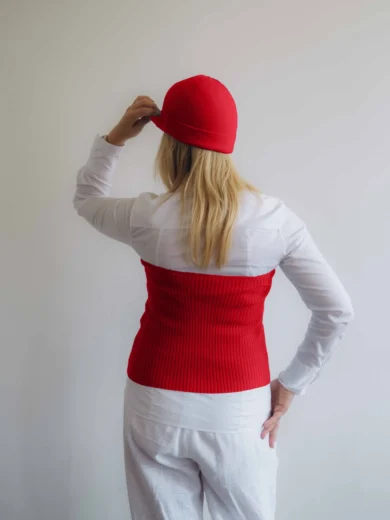 Modelka v bielom outfite s červeným pleteným dvojsetom MAGNHILD – driekovník a čiapka TATTJA, pohľad zozadu