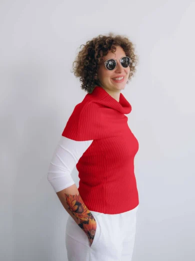 Modelka v bielom outfite TATTJA s červeným pleteným dvojsetom RAGNILD – nákrčník a driekovník, pohľad zboku