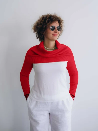 Modelka v bielom outfite TATTJA s červeným pleteným dvojsetom RIGMOR – nákrčník a rukávniky, pohľad spredu