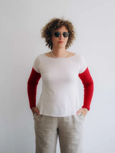 Modelka v bielom outfite s červenými pletenými rukávnikmi KATJA značky TATTJA, pohľad spredu
