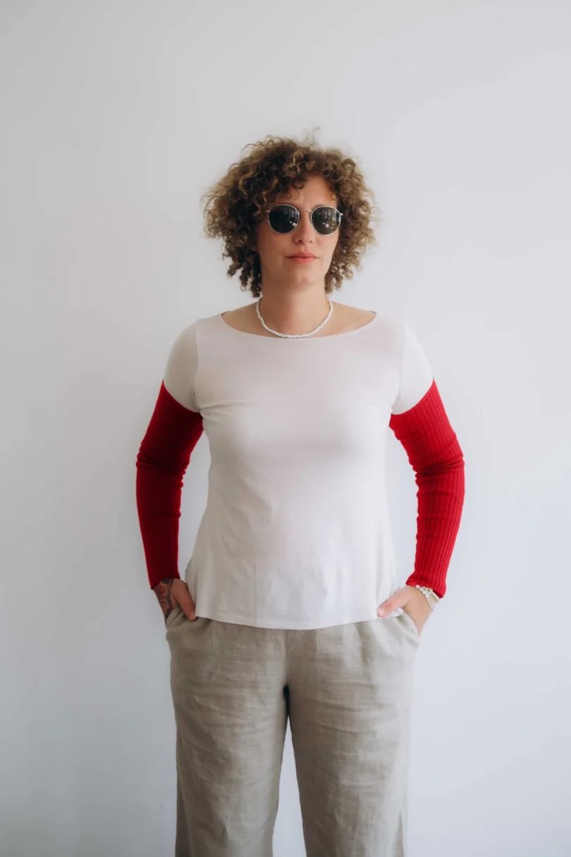 Modelka v bielom outfite s červenými pletenými rukávnikmi KATJA značky TATTJA, pohľad spredu