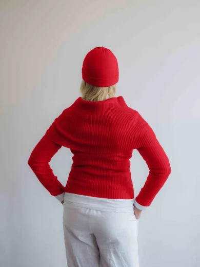 Modelka v bielom outfite s červeným pleteným štvorsetom TATTJA – nákrčník, driekovník, rukávniky a čiapka, pohľad zozadu