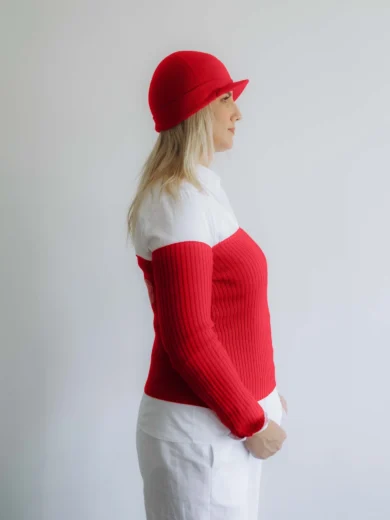 Modelka v bielom outfite s červeným pleteným trojsetom GUNVAR značky TATTJA – driekovník, rukávniky a čiapka, pohľad zboku
