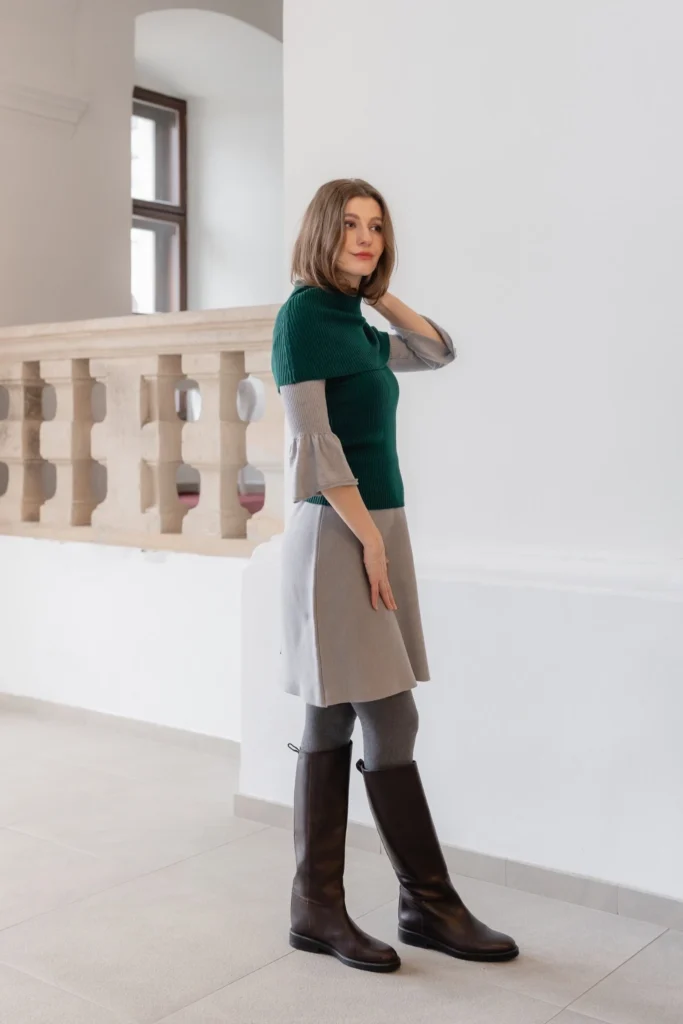 Side view of grey dress styled with green knit neck warmer and fitted knit top – elegant layered outfit